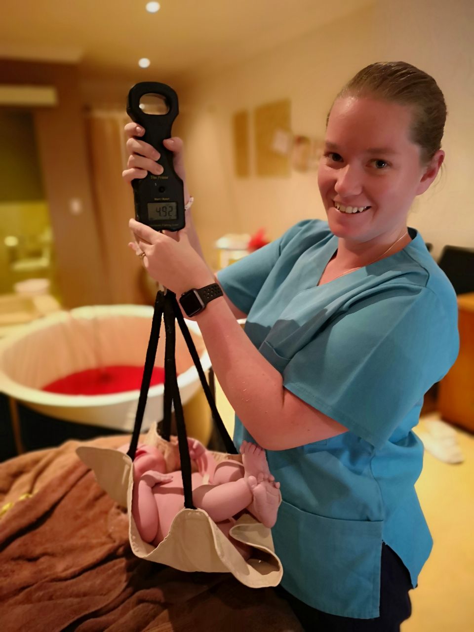 Sarah weighing newborn after vbac birth at genesis clinic